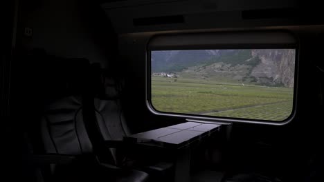 dark interior view of empty leather business class seats travelling through switzerland with train through scenic landscapes