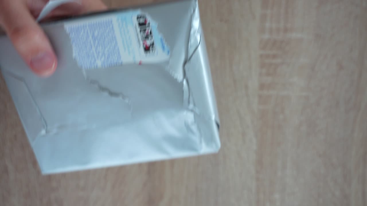 나무 테이블 위 에 물음표 가 그려진 패키지 를 풀고 있는 사람