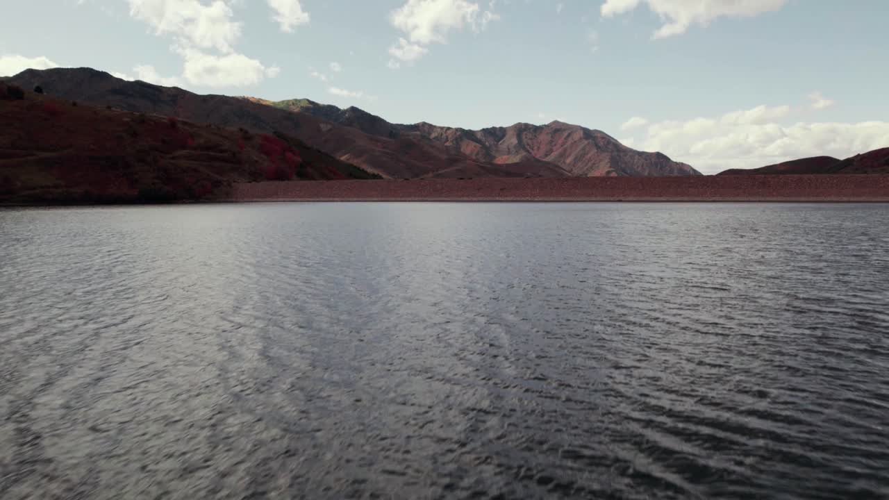 un dron volando bajo sobre el lago se eleva para revelar las cadenas montañosas en salt lake city, utah a 60 fps.