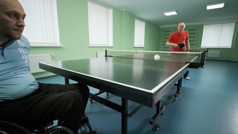 a man in a wheelchair plays ping pong. people with disabilities play table tennis. rehabilitation of the disabled. sport.