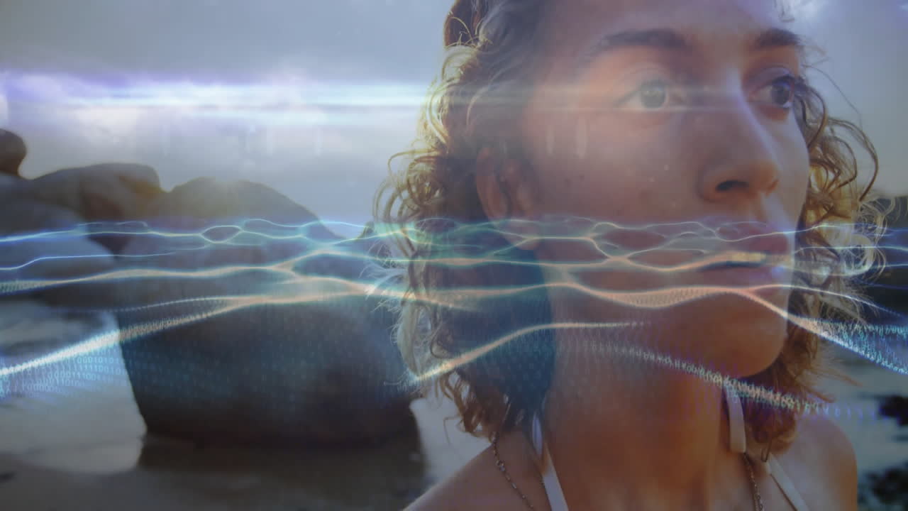 On beach, woman with animation of abstract light waves overlaying her face
