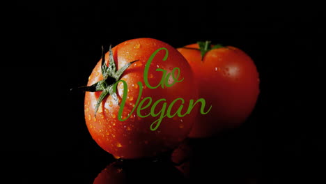 Animation-of-go-vegan-text-over-tomatoes-on-black-background