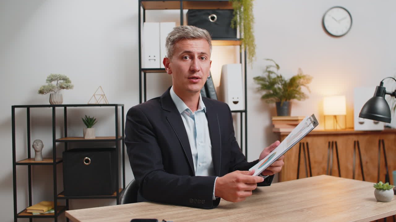 уверенный в себе молодой бизнесмен показывает графический анализ во время видеозвонка на домашнем офисном столе