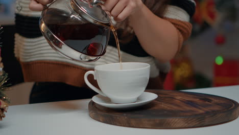 Close-up-of-pouring-beverage-from-tea-kettle-at-festive-home