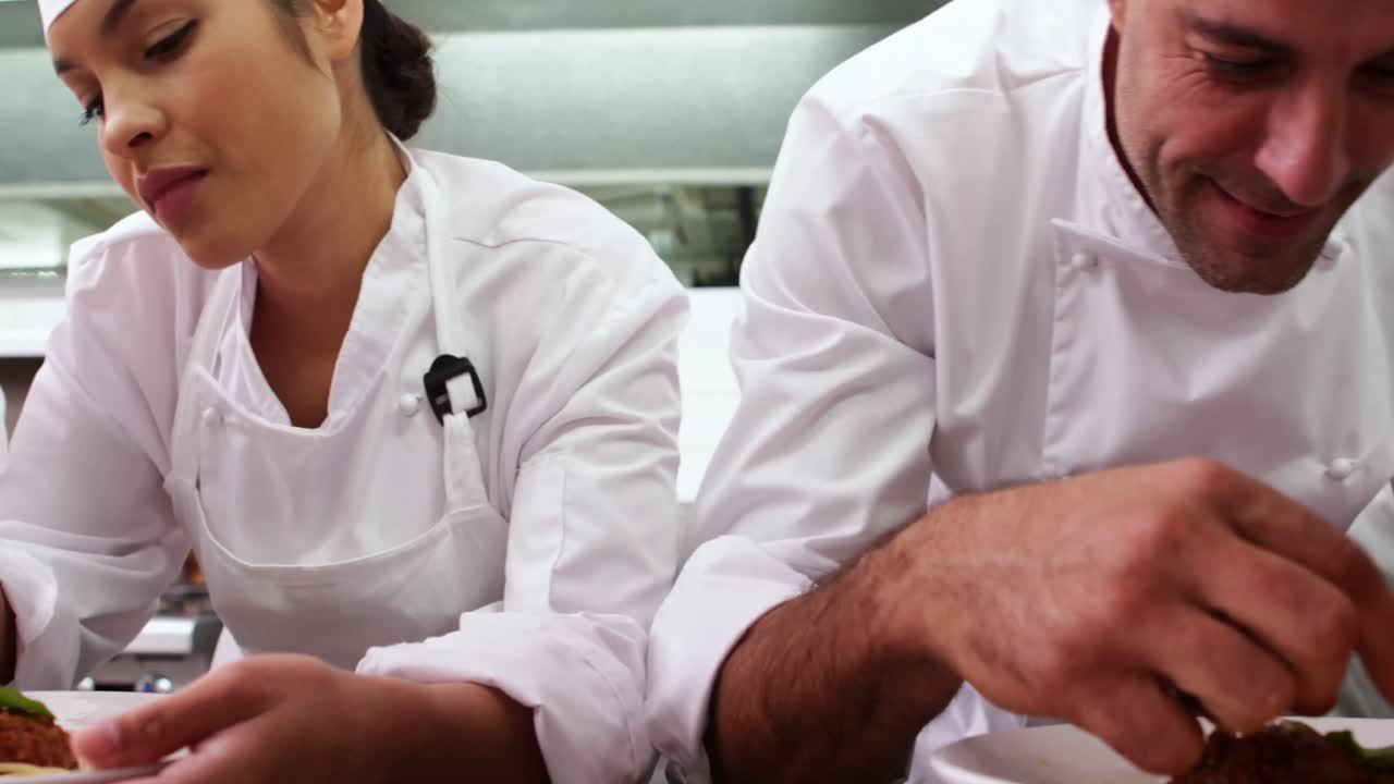 Row of chefs garnishing spaghetti dishes with basil leaf