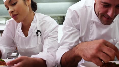fila de chefs adornando platos de espagueti con hojas de albahaca