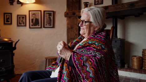 mujer anciana tejiendo junto a la chimenea