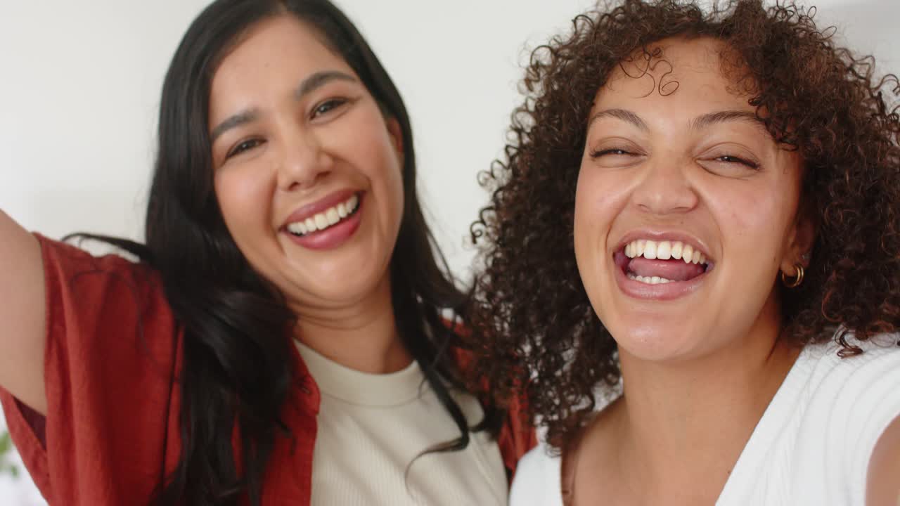 Amigas diversas inclinándose y riendo, compartiendo un chiste, alcanzando la lente, revelando una lámpara y aros.
