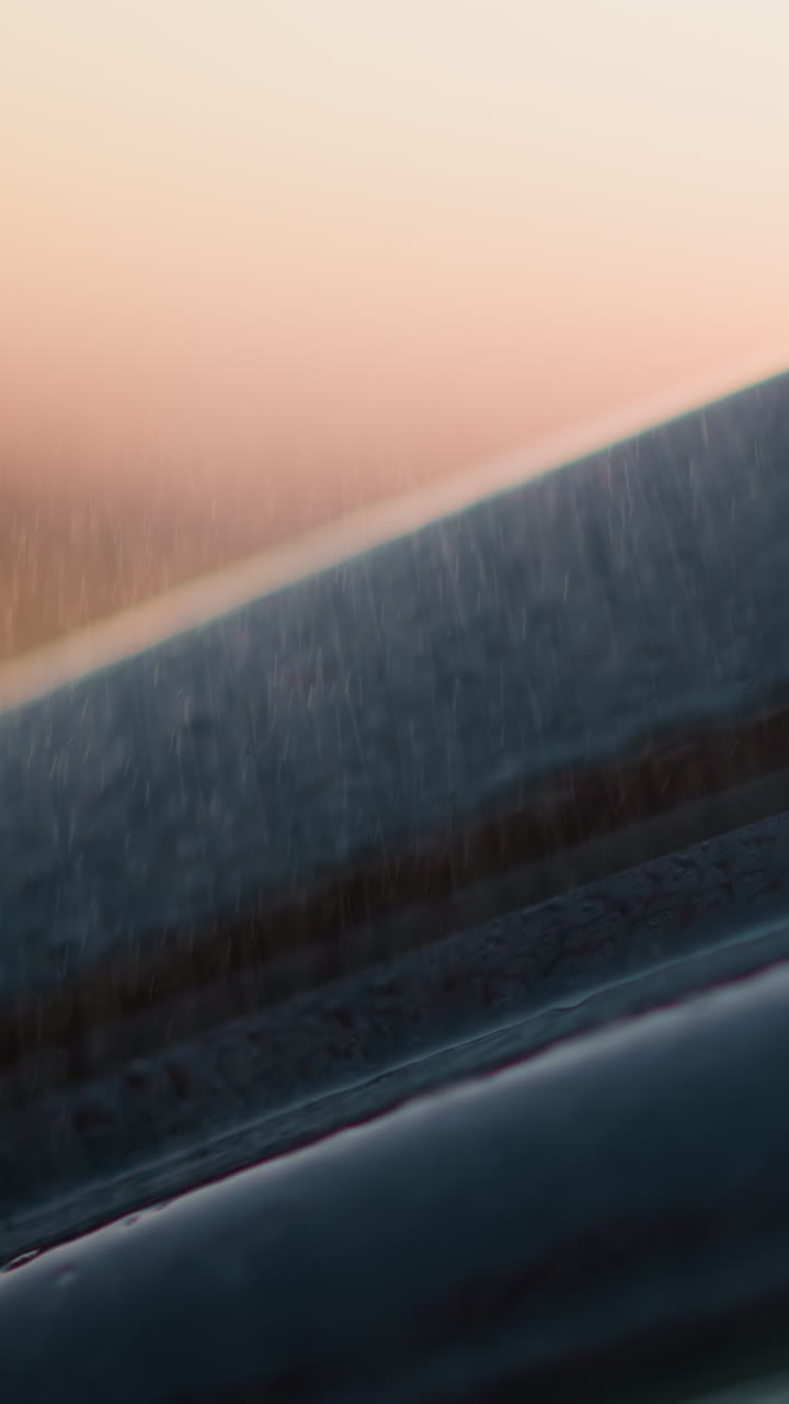 Car under rainstorm at dusk time closeup. Vehicle surface with clear water drops at rainstorm in evening countryside. Driving auto at rainfall