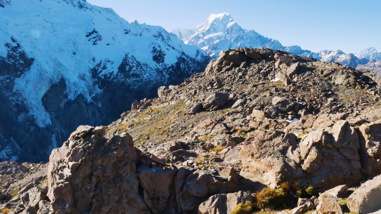 rocky mountain top with snow covered mountains in background