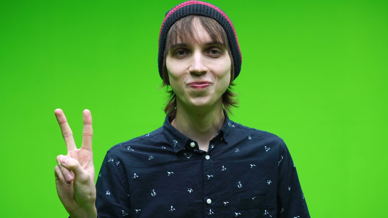 joven haciendo el símbolo de la victoria contra un fondo de llave de croma extraíble