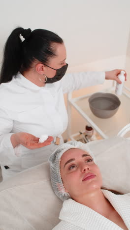 cosmetologist applies cleansing foam to woman face during skincare massage procedure beauty clinic