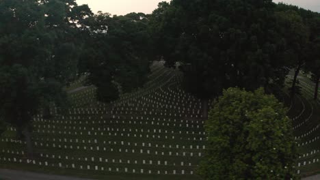 aerial view of rows of white gravestones in a vast national cemetery with trees and pathways