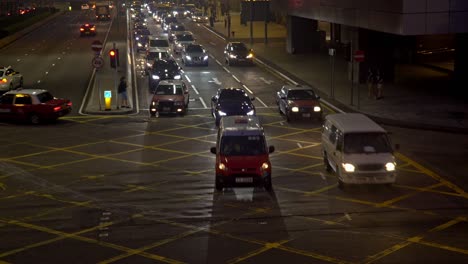 el tráfico cruza una calle concurrida en la isla de hong kong por la noche