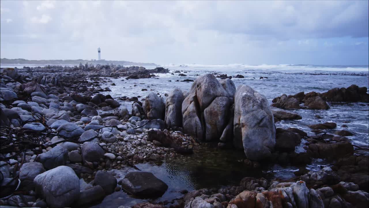 formaciones rocosas en hangklip bay con faro en segundo plano.