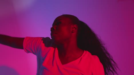 toma de estudio de una joven bailarina bailando contra un fondo iluminado de azul y rosa 4