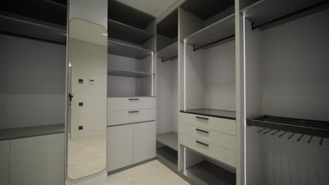 a well-organized wardrobe room displays tall, modern cabinets with ample shelving and integrated lighting, creating a sophisticated and functional clothing storage area with a comfortable chair for dressing.