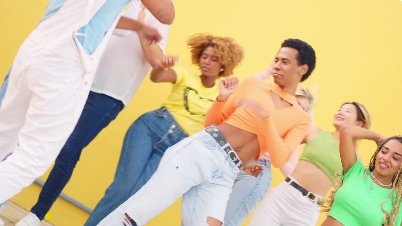 Group of young people dancing in front of a yellow wall