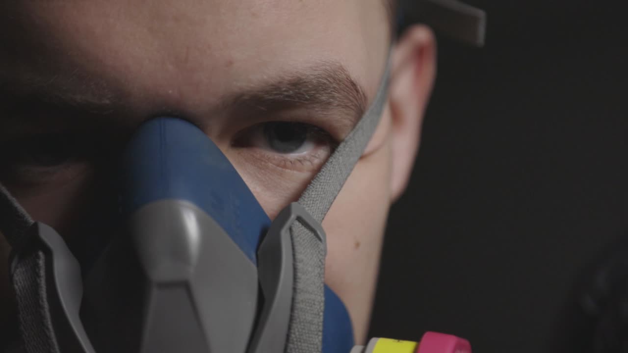 A young man wearing a multi-purpose respirator half mask for health protection - Close-up Shot