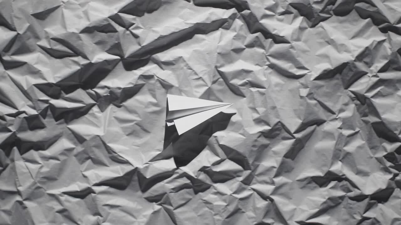 Top-down view of a paper airplane on crumpled paper, evoking creativity and simplicity