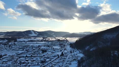 Hermosa-Toma-Aérea-De-La-Ciudad-Y-Las-Montañas-Cubiertas-De-Nieve-En-Japón