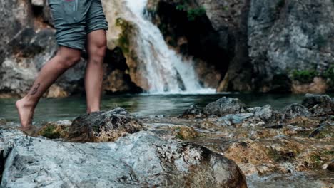person walking barefoot near a waterfall