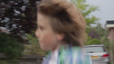 Young-boy-running-through-a-beautiful-suburban-neighborhood