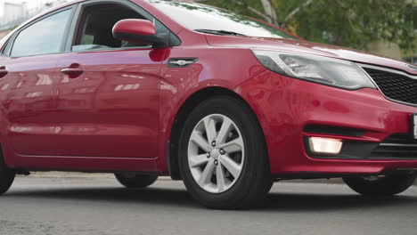 elegant red car drives on asphalt road in center of city