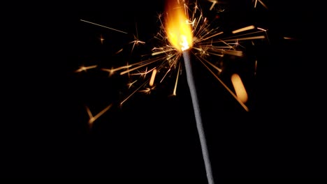 bengal fire sparkling lights burning in front of black background, close-up 4k footage, slow motion