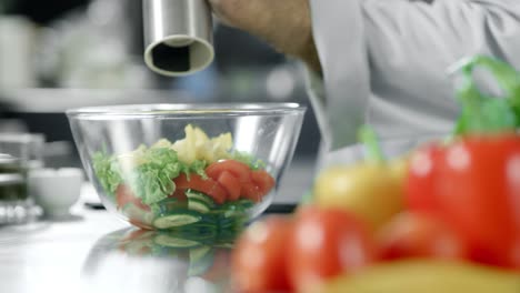 Chef-peppering-salad-at-kitchen-restaurant.-Closeup-hands-peppering-vegetables.