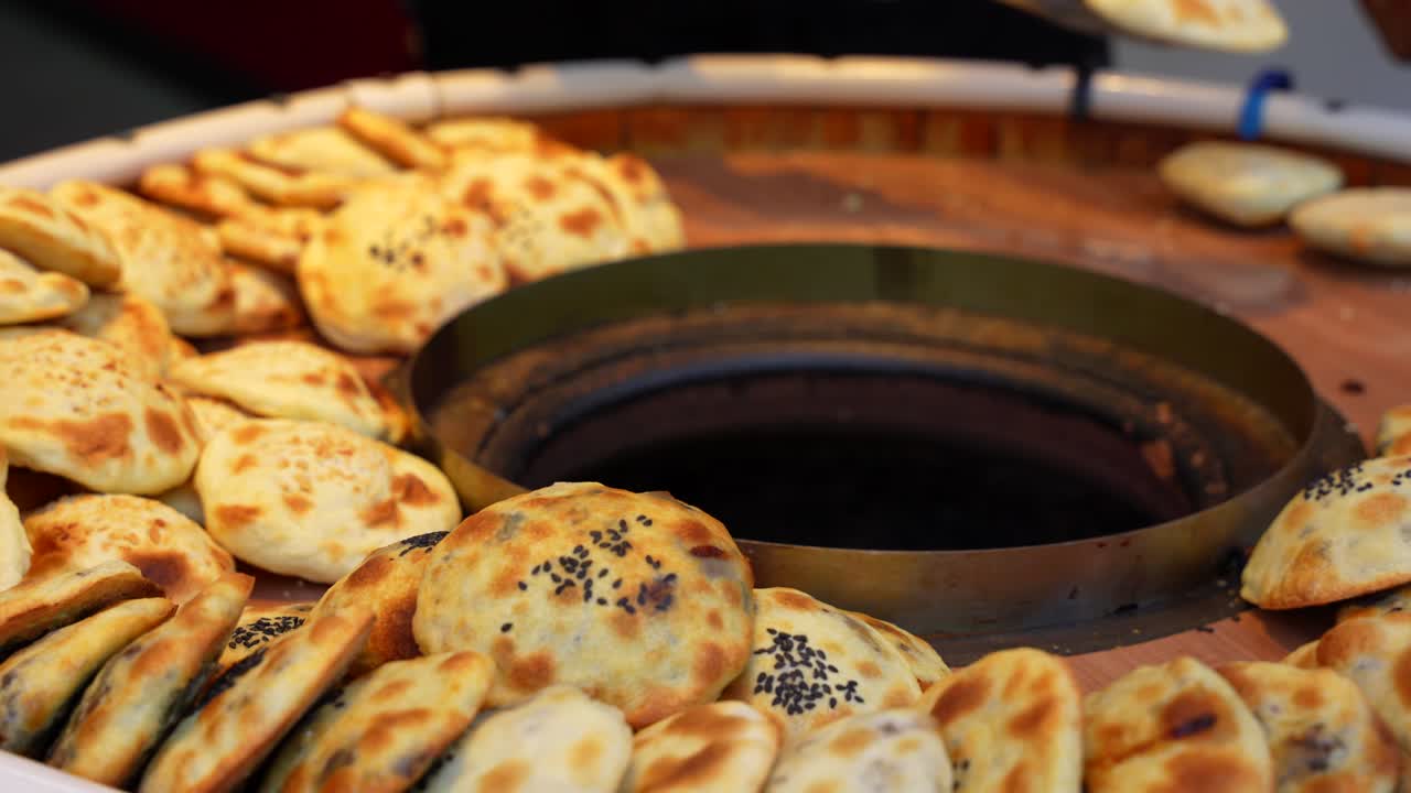 Hand picks fresh, traditional sesame shaobing order from hot tandoor oven