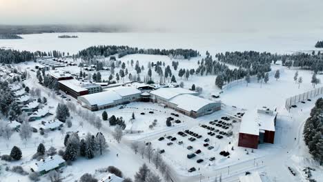 Drone-shot-orbiting-the-holiday-area-of-Katinkulta,-winter-sunset-in-Vuokatti,-Finland