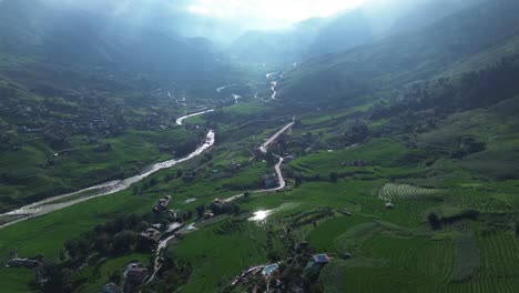 Aerial pan left capturing layered rice terraces and village huts among greenery
