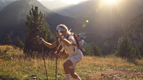 Mujer-Rubia-Caminando-Cuesta-Arriba-Con-Bastones-De-Trekking,-Benasque,-España,-Plano-Medio