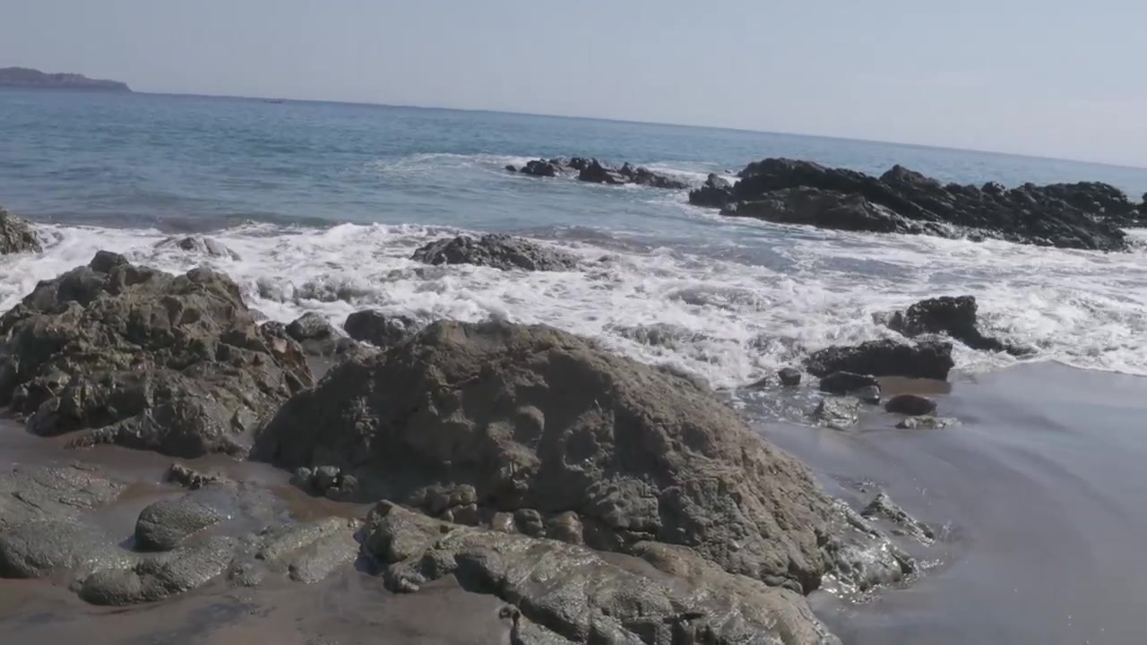 Onde dell'oceano che si infrangono contro una costa rocciosa in una giornata di sole