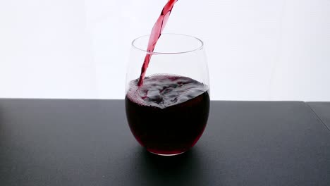 vino tinto burdeos vertido en la copa de vino sobre fondo blanco