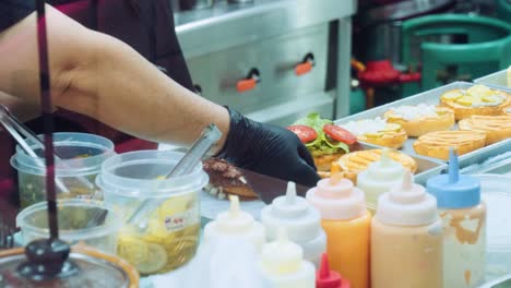 4K-Cinematic-food-cooking-footage-of-a-chef-preparing-and-making-a-delicious-homemade-burger-in-a-restaurant-kitchen-in-slow-motion-by-putting-the-different-toppings-and-burgers-on-the-buns