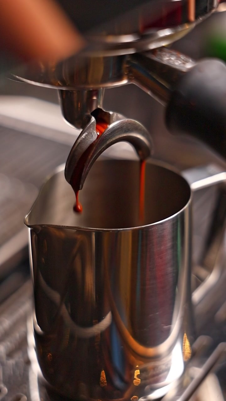 Espresso che cola dal portafiltro in una lattiera di metallo
