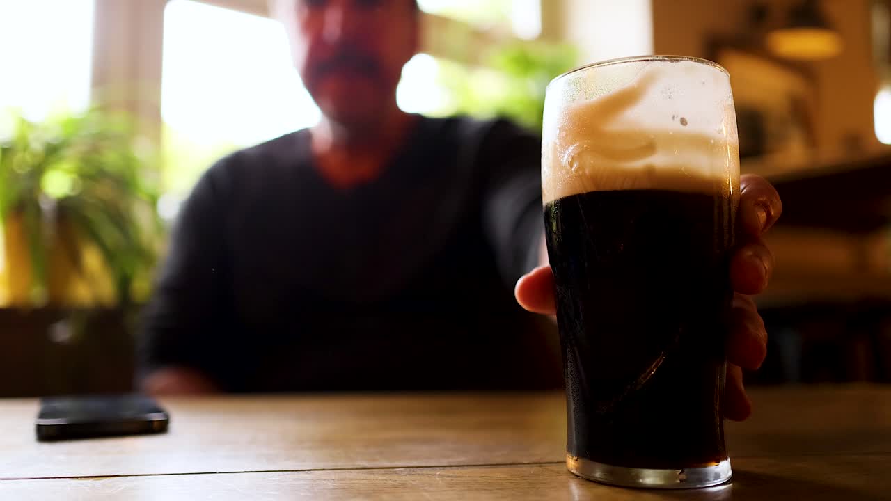 Man drinks and places stout on table