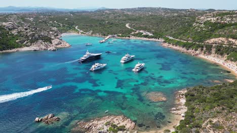 Isla-De-La-Maddalena,-Caprera,-Cerdeña---Barcos-Y-Yates-En-La-Bahía-Azul-Turquesa---Antena-4k