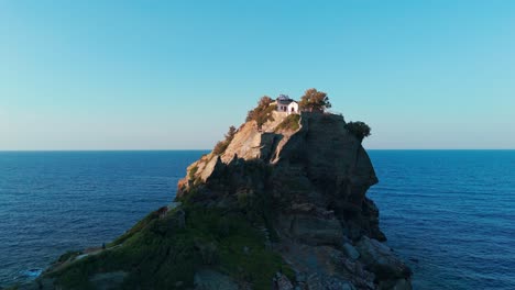 isla rocosa en el medio del mar azul durante la puesta del sol con árboles en la parte superior, vista aérea