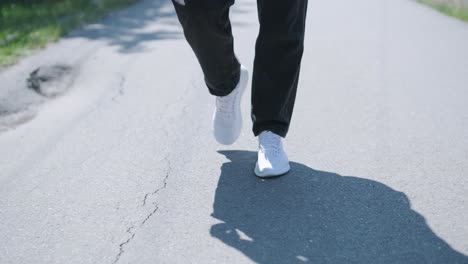 young man walking with guitar on street near forest