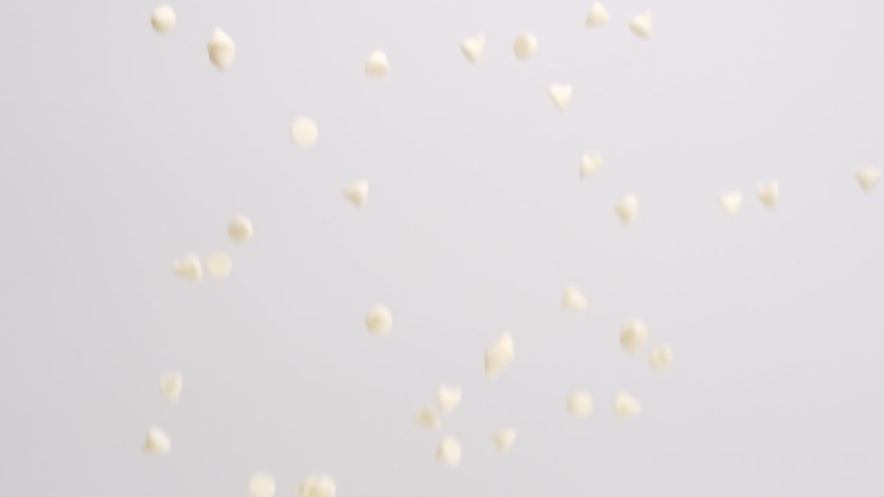 슬로우 모션으로 흰색 배경에 흰색 초콜릿 칩 비가 내림