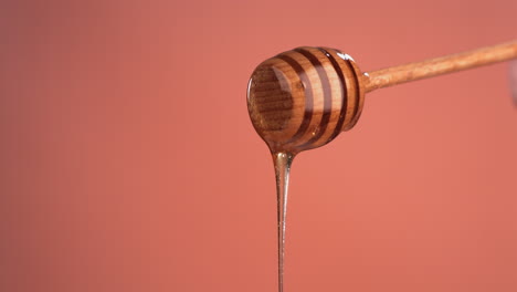 super slow motion cu honey pouring from honey stick against bright background