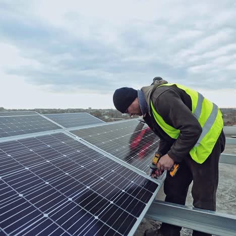 technician with drill strengthens solar panel. installation of photovoltaic cells on metal basis on the roof of a building. alternative source of energy.