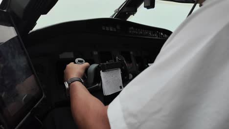 close-up left side view of a white pilot operating the flight controls inside a jet cockpit while flying inside a storm with turbulence