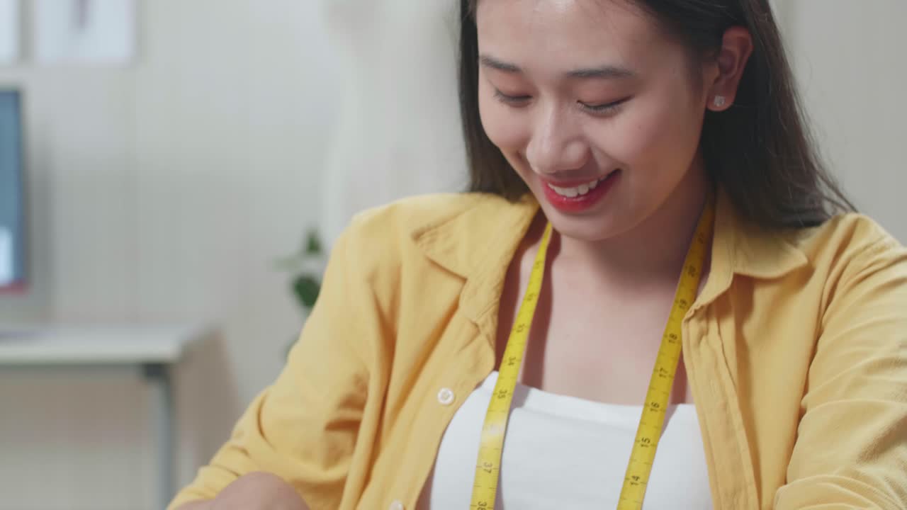 아시아 여성 디자이너가 미래의 드레스의 템플릿을 만니다. 그녀는 세부 사항의 도자기 윤을 그립니다.