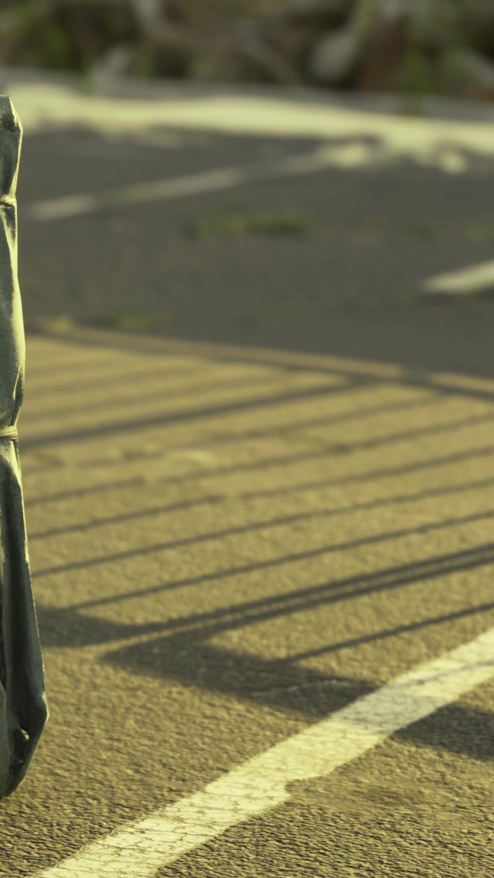 Backpack rests on pavement while shadows fall from a nearby fence
