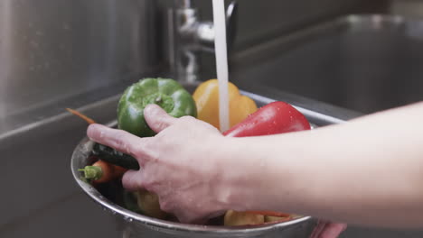 chef caucásico lavando verduras en el fregadero en la cocina, cámara lenta