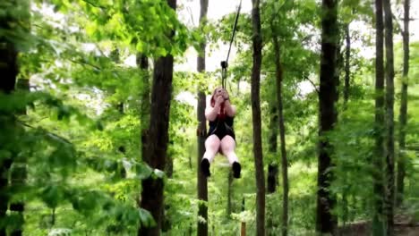 woman ziplining through forest